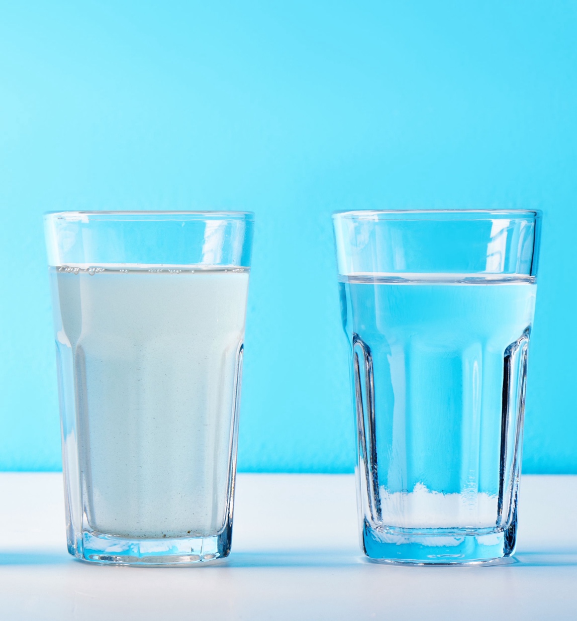 Two glasses of water where the left one is cloudy/opaque and the right one is pure and clear